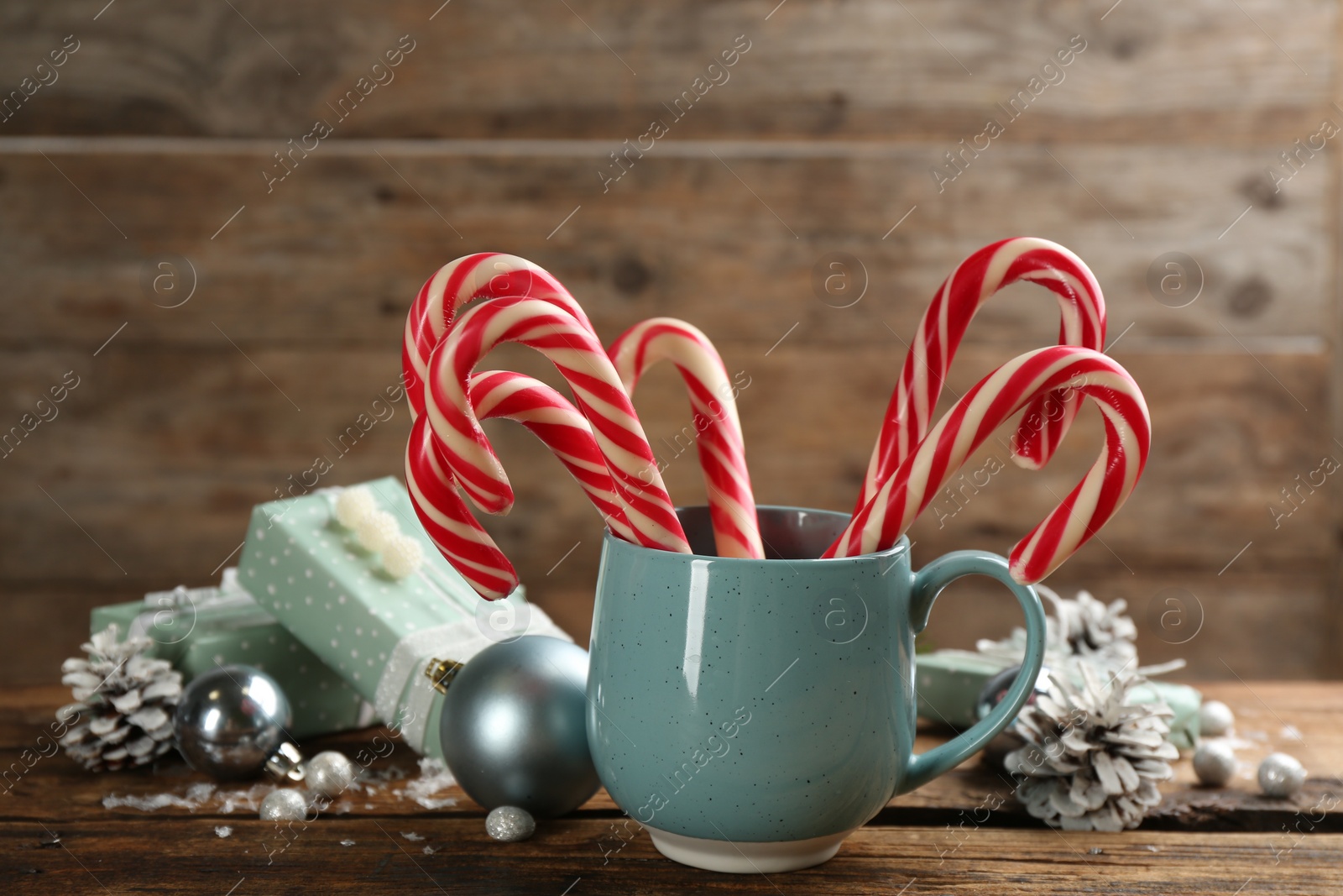 Photo of Many sweet candy canes, gift boxes  and Christmas decor on wooden table