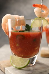 Photo of Tasty shrimp cocktail with sauce in glass and lime on table, closeup
