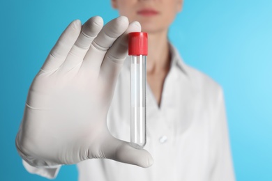 Photo of Female doctor holding empty test tube on color background, closeup. Medical object