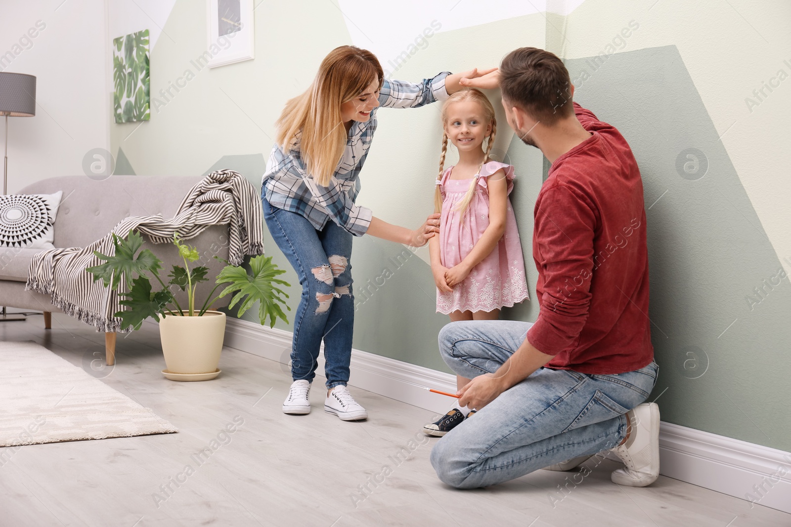 Photo of Parents measuring their daughter's height at home