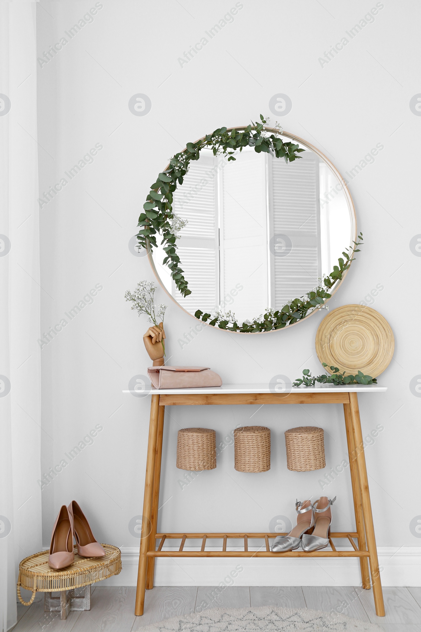 Photo of Round mirror and table with accessories near white wall. Modern interior design