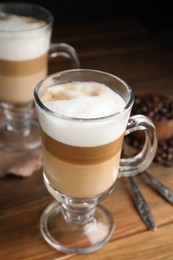 Photo of Delicious latte macchiato and coffee beans on wooden table