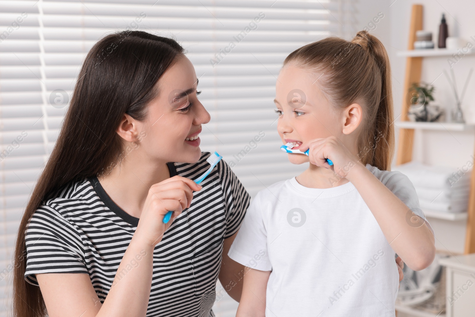 Photo of Mother and her daughter brushing teeth together in bathroom