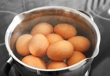 Cooking chicken eggs in pot on electric stove, closeup view