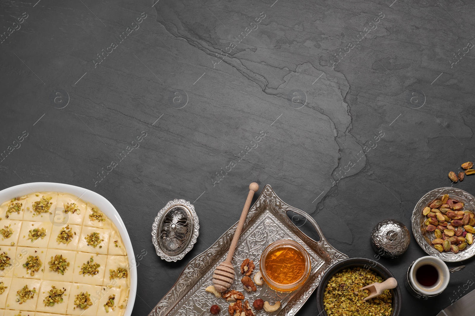 Photo of Making delicious baklava. Raw dough with ingredients on black textured table, flat lay and space for text