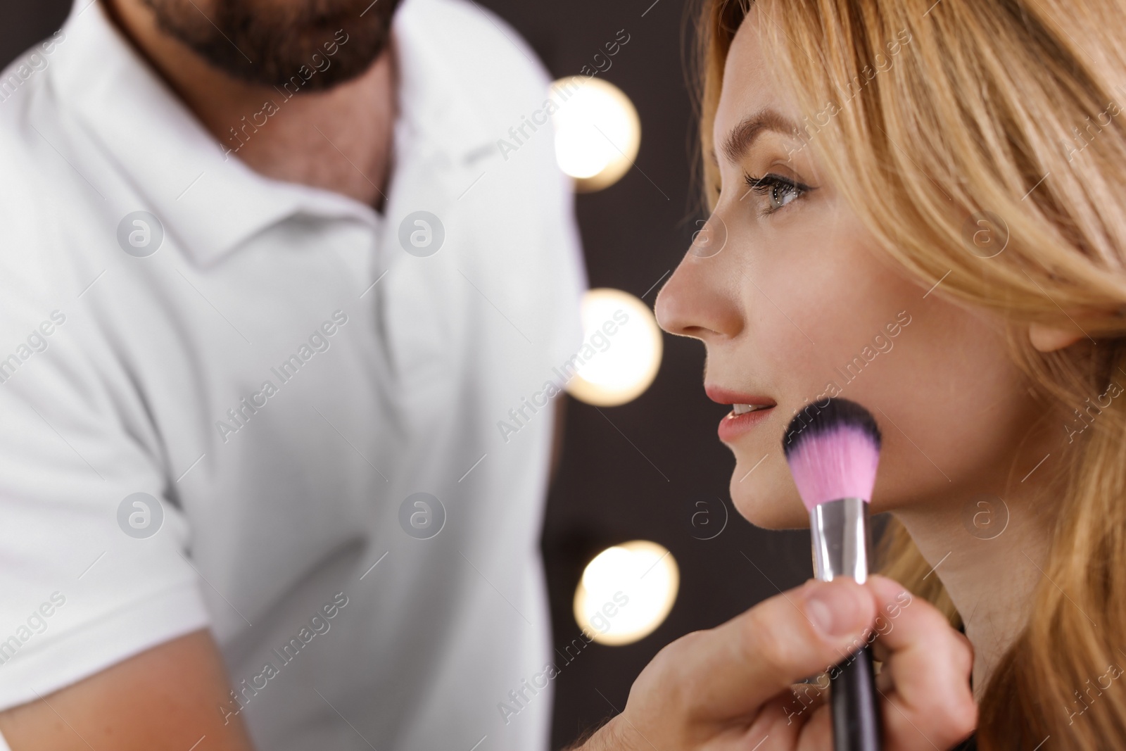 Photo of Professional makeup artist working with client in dressing room