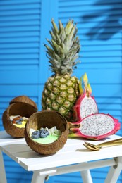 Photo of Tasty smoothie bowl served in coconut shells on white wooden table