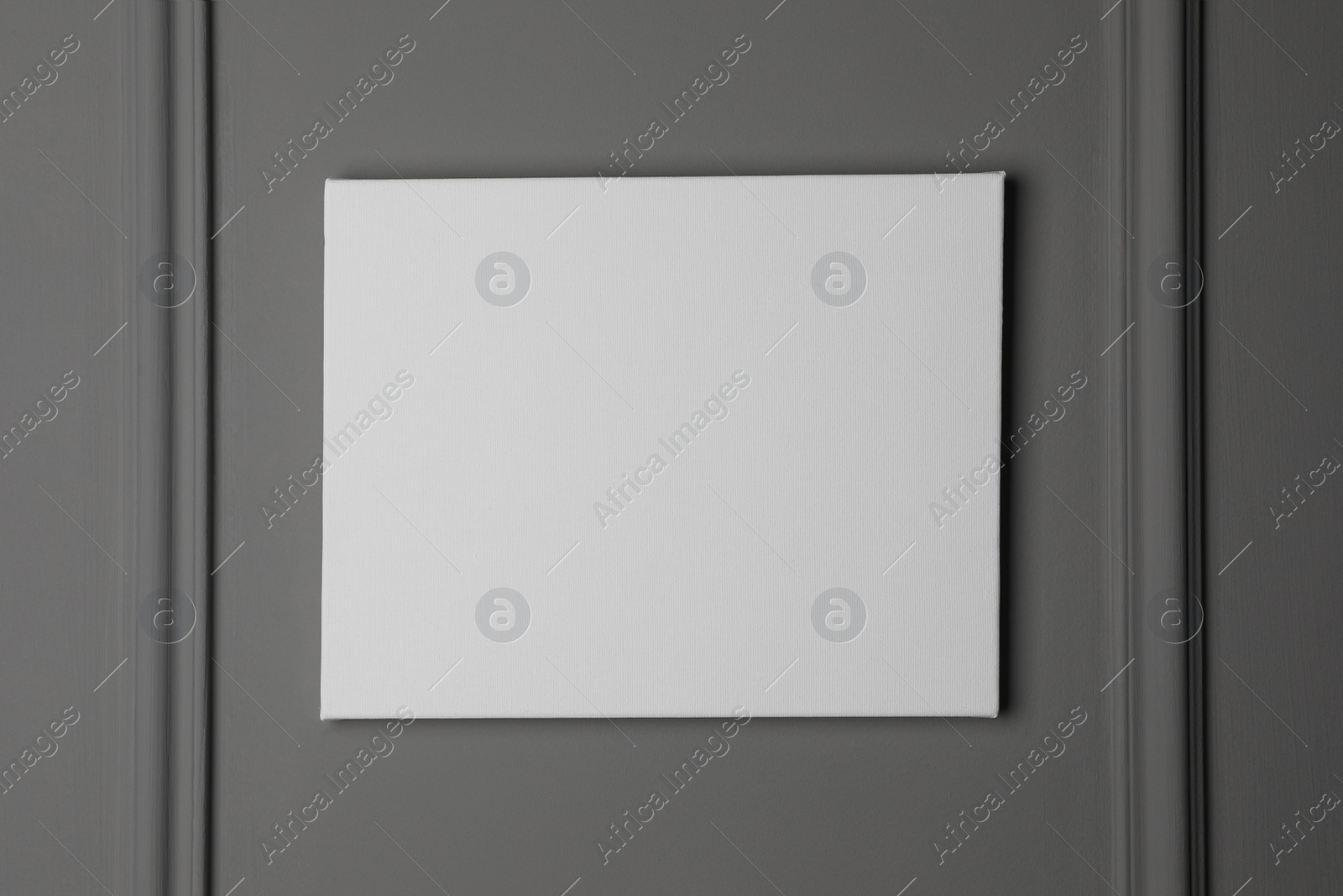 Photo of Blank canvas hanging on grey wall, space for text