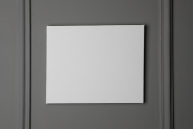 Blank canvas hanging on grey wall, space for text