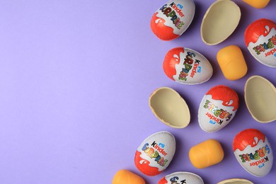 Sveti Vlas, Bulgaria - June 29, 2023: Kinder Surprise Eggs and plastic capsules on violet background, flat lay. Space for text