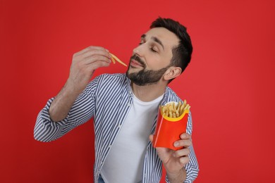 Man eating French fries on red background