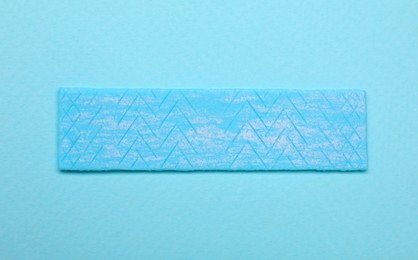 One stick of chewing gum on turquoise background, top view