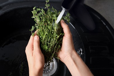 Woman washing aromatic thyme in sink, above view