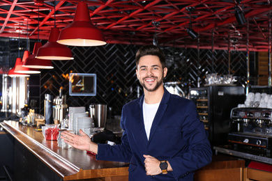 Photo of Young business owner standing near counter in his cafe
