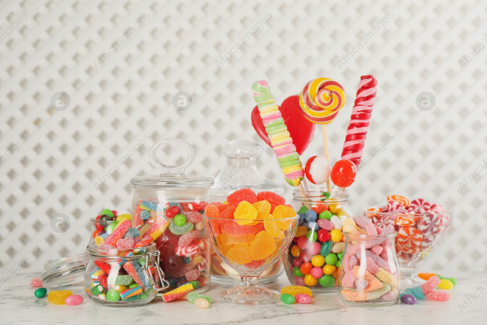 Photo of Jars with different delicious candies on white marble table