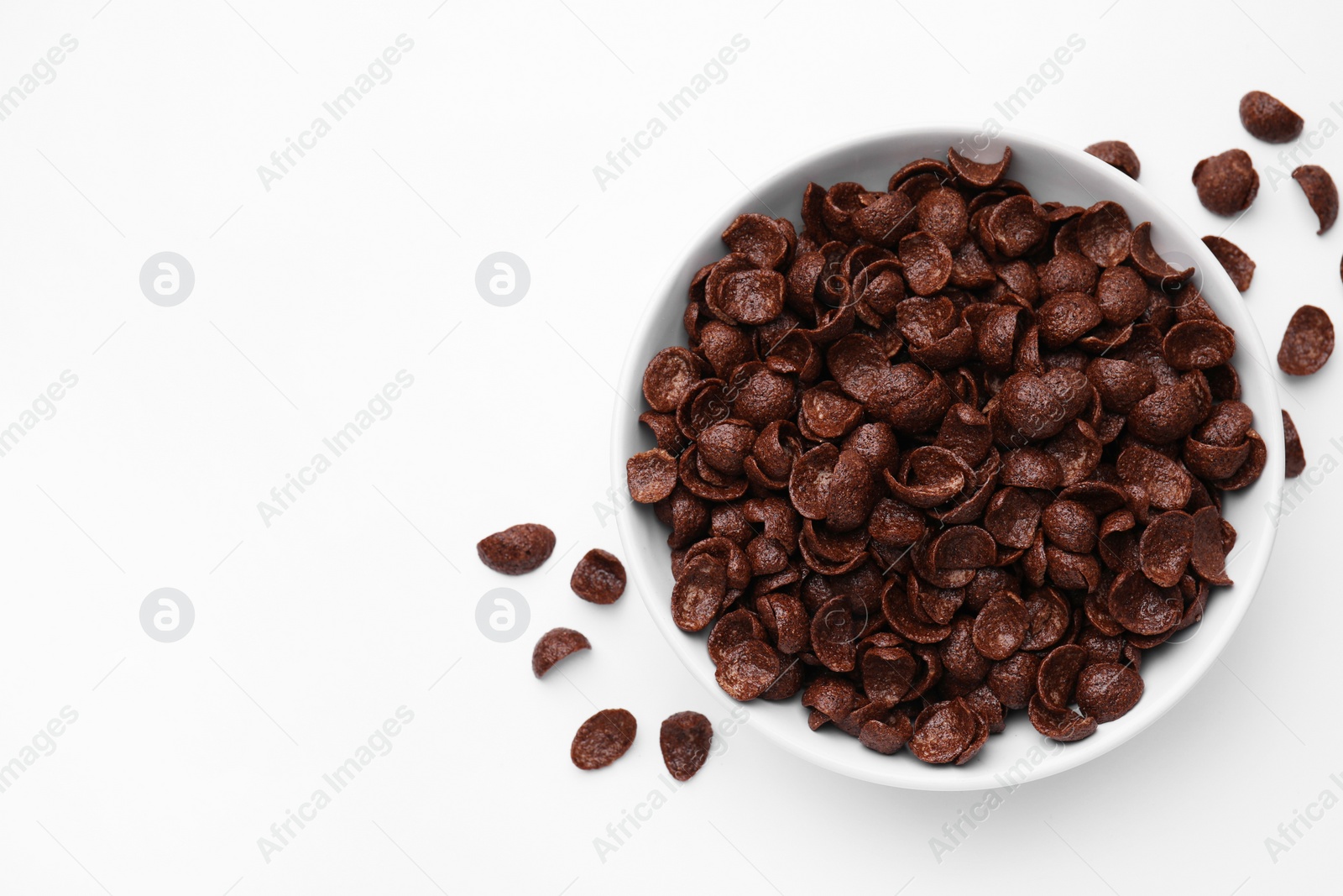 Photo of Breakfast cereal. Chocolate corn flakes in bowl on white table, top view. Space for text