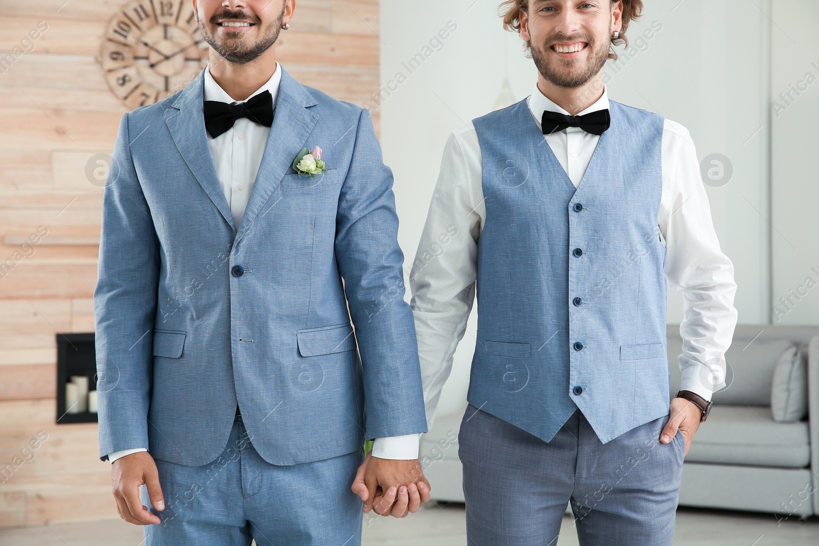 Photo of Happy newlywed gay couple in suits at home