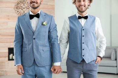 Happy newlywed gay couple in suits at home