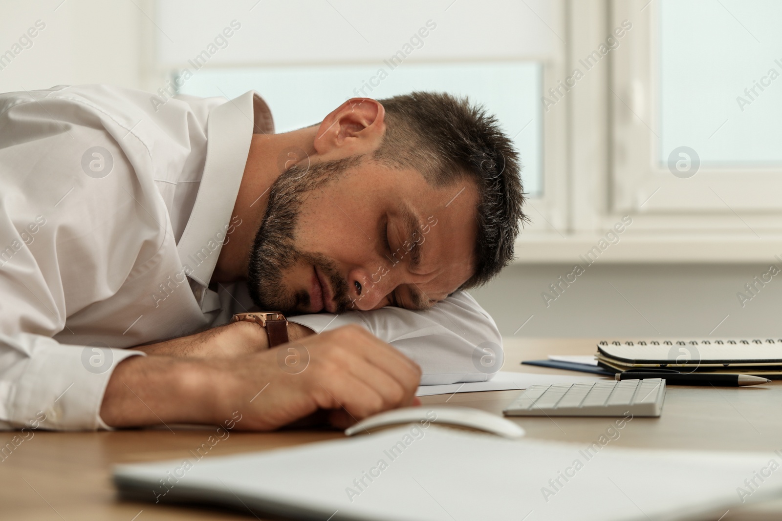 Photo of Tired man sleeping at workplace in office