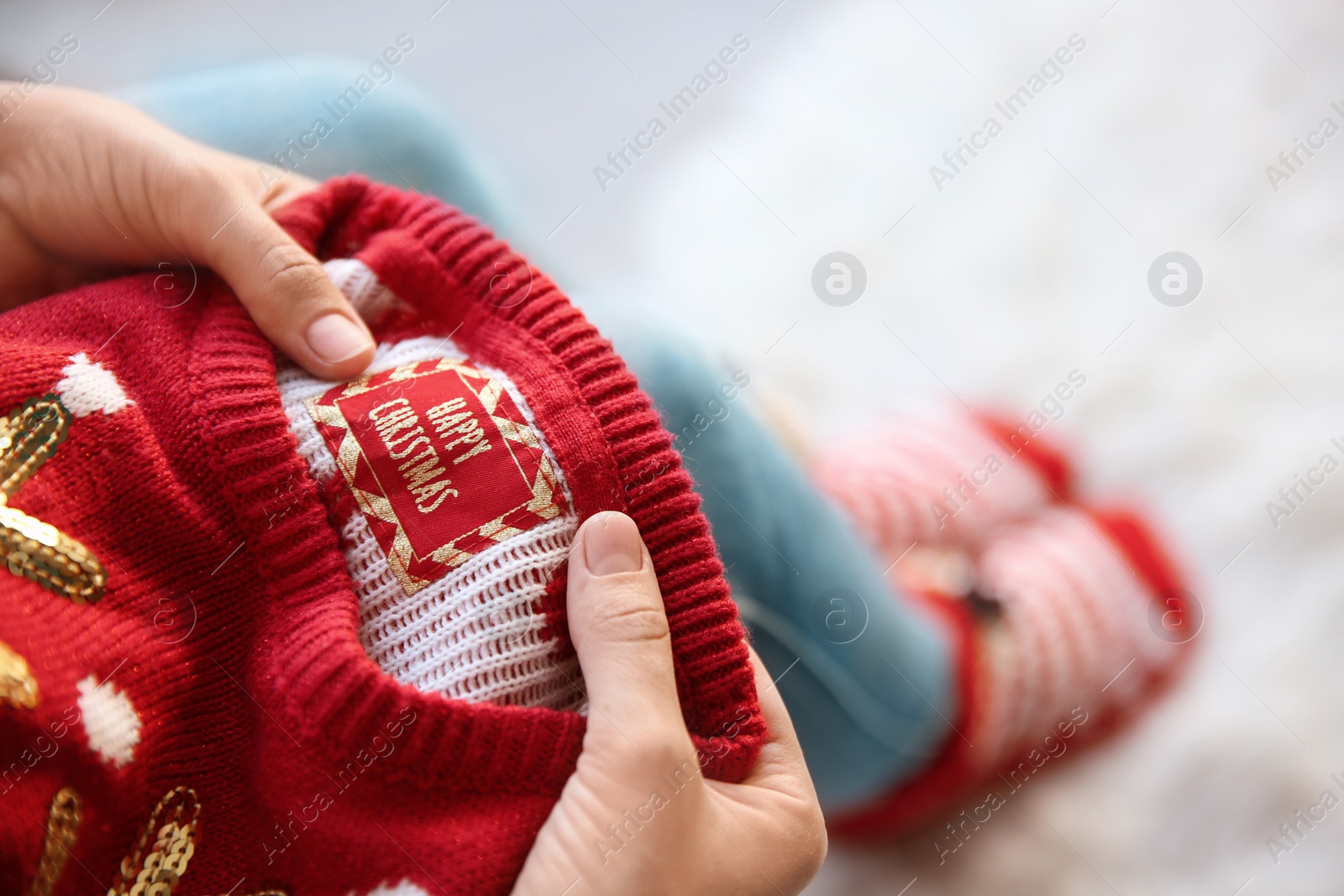 Photo of Woman holding Christmas sweater with tag, closeup