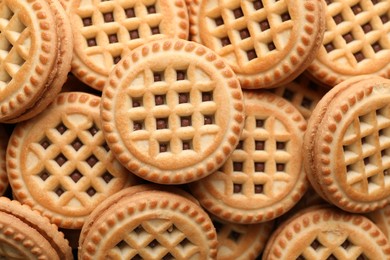 Tasty sandwich cookies with cream as background, top view