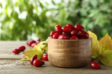 Photo of Fresh ripe dogwood berries with green leaves on wooden table