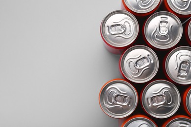 Energy drink in cans on grey background, top view. Space for text