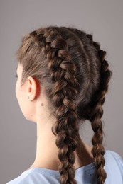 Woman with braided hair on grey background