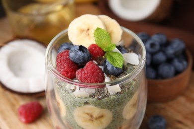 Photo of Tasty chia matcha pudding and fruits on wooden table, closeup. Healthy breakfast