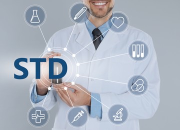 Image of STD prevention. Closeup view of doctor with drug, abbreviation and different icons on light background