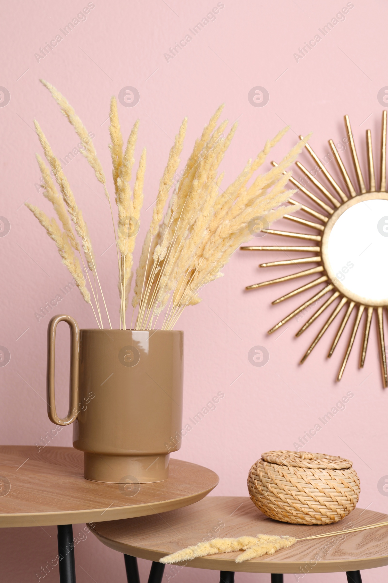 Photo of Stylish ceramic vase with dry flowers on wooden table near pink wall