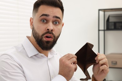 Confused man with empty wallet in office