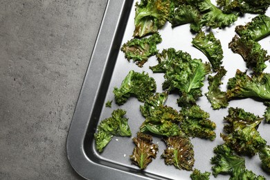 Photo of Tasty baked kale chips on grey table, top view