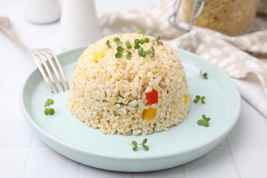 Delicious bulgur with vegetables and microgreens served on table, closeup