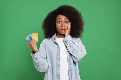 Photo of Confused woman with credit cards on green background. Debt problem