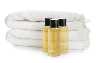 Photo of Mini bottles with cosmetic products and towels on white background. Hotel amenities