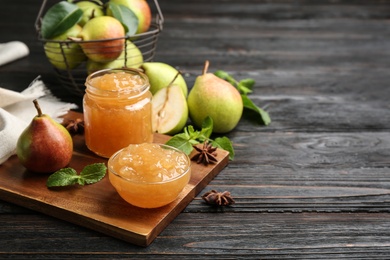 Delicious pear jam and fresh fruits on black wooden table. Space for text