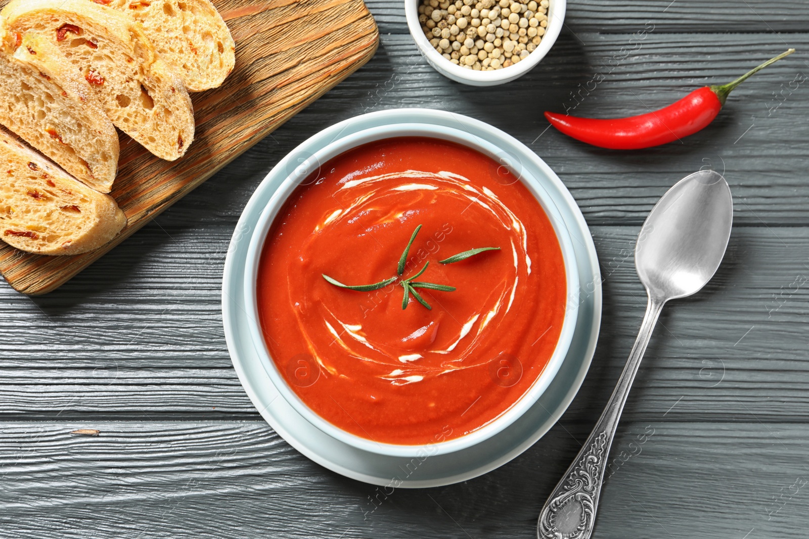 Photo of Fresh homemade tomato soup served with bread on wooden table, top view