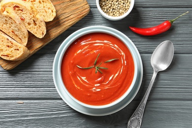 Fresh homemade tomato soup served with bread on wooden table, top view