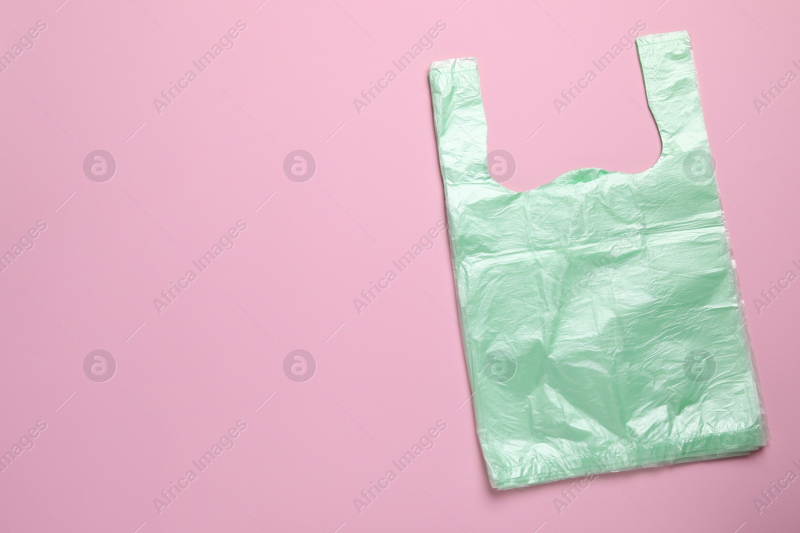 Photo of Pack of plastic bags on pink background, top view. Space for text