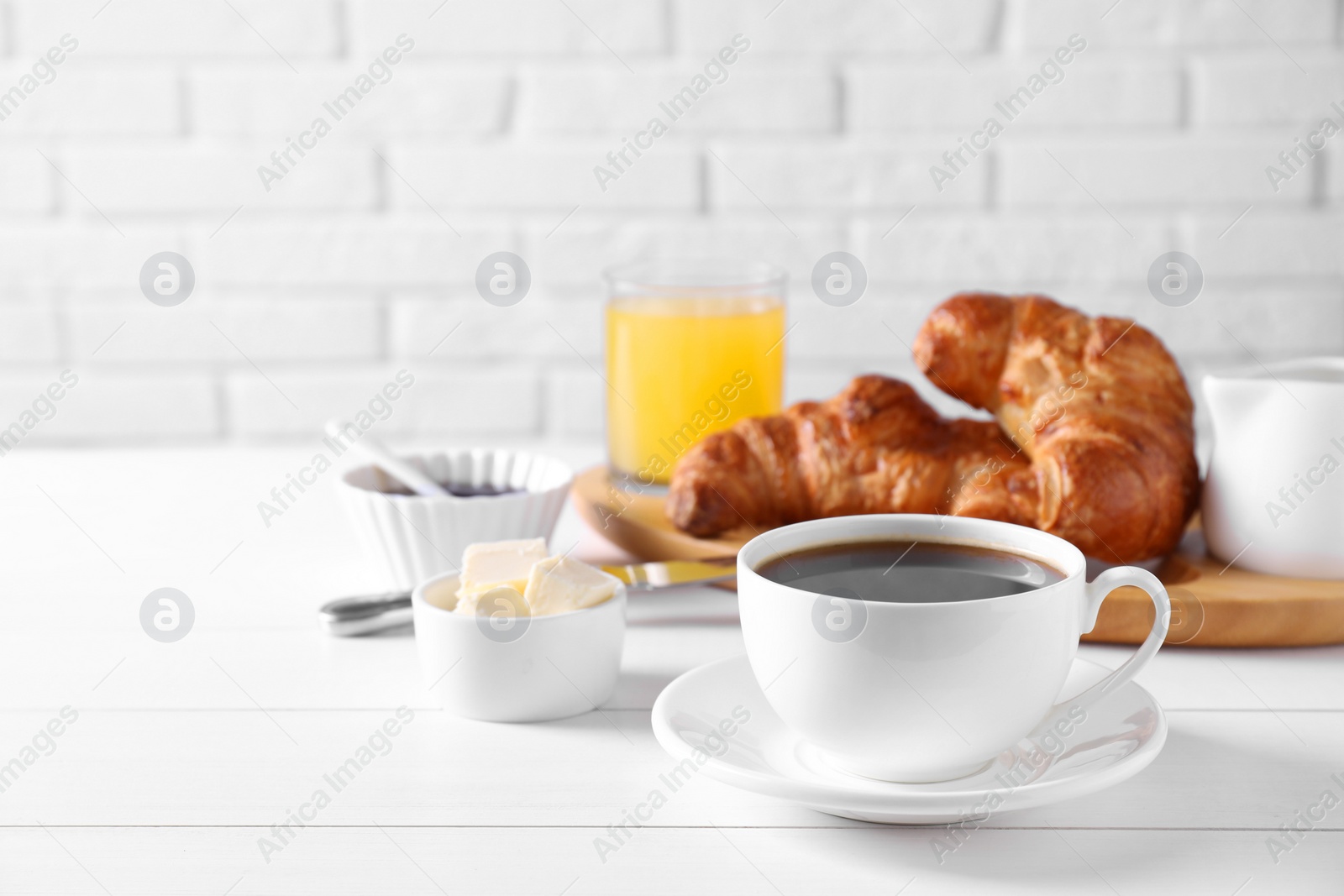 Photo of Breakfast time. Fresh croissants, butter and coffee on white wooden table. Space for text