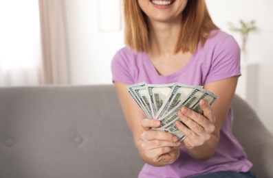 Smiling woman with money on sofa, closeup. Space for text