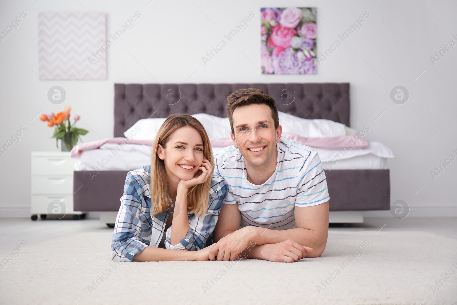 Photo of Lovely young couple lying on cozy carpet at home