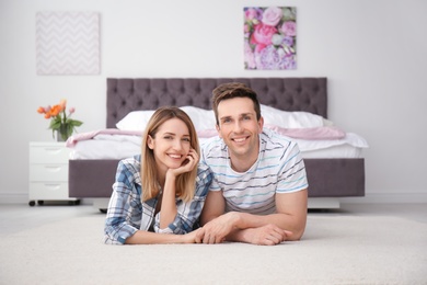 Photo of Lovely young couple lying on cozy carpet at home