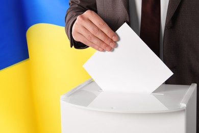 Image of Man putting his vote into ballot box against national flag of Ukraine, closeup. Space for text