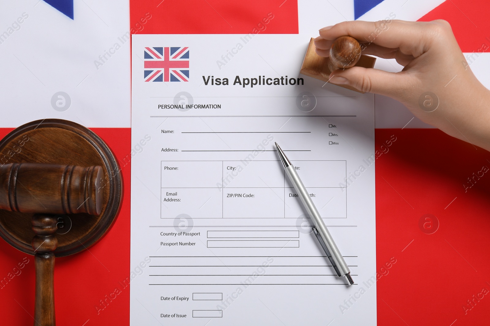 Photo of Immigration to United Kingdom. Woman stamping visa application form on flag, top view