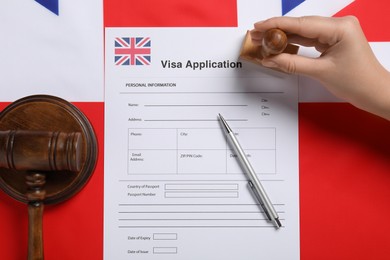 Immigration to United Kingdom. Woman stamping visa application form on flag, top view