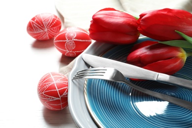 Photo of Festive Easter table setting with painted eggs on wooden background, closeup