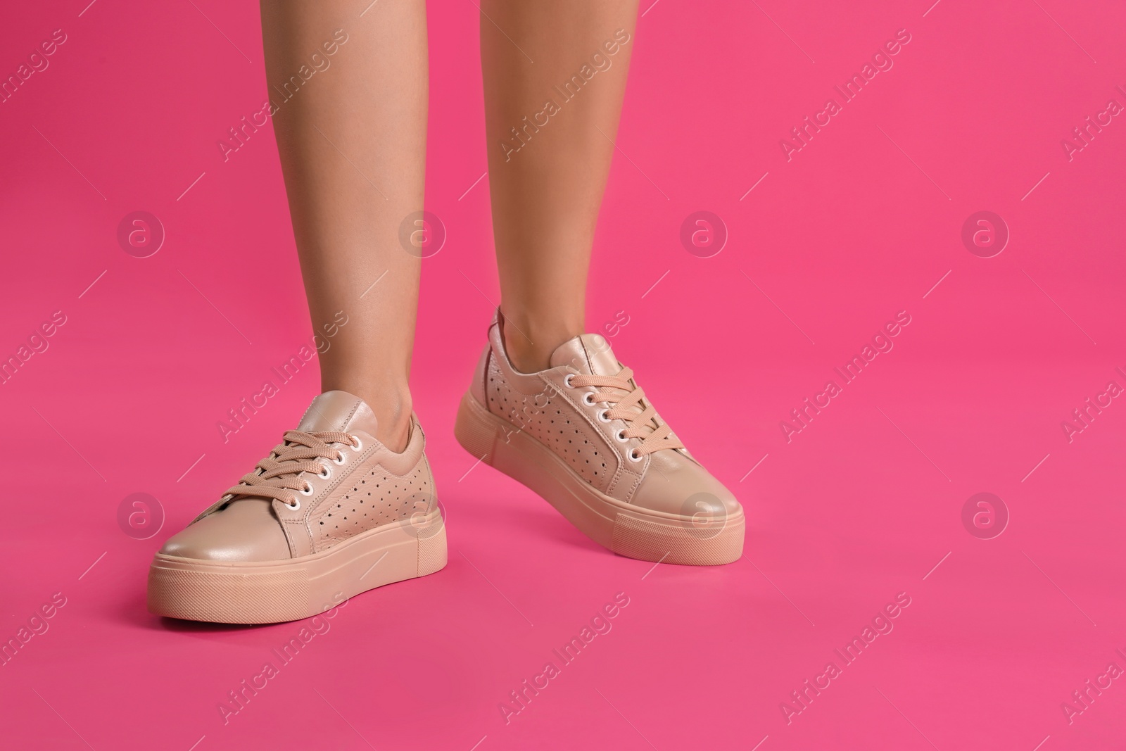 Photo of Woman wearing shoes on pink background, closeup