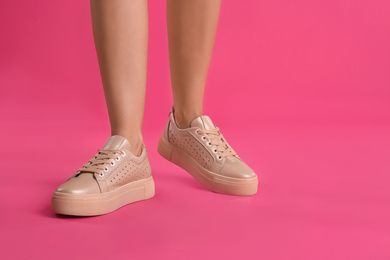 Woman wearing shoes on pink background, closeup